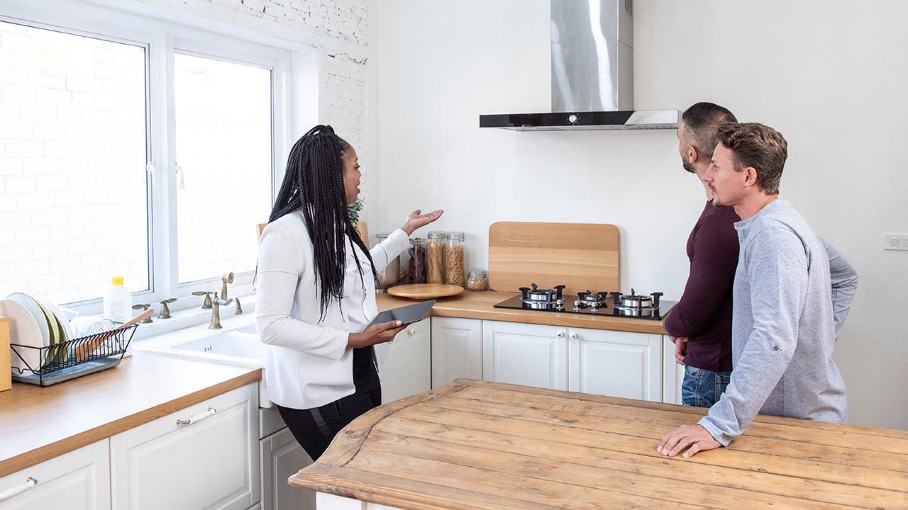 Female real estate agent showing gay couple around new house