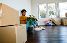 woman sitting on the floor in her new house with boxes around her