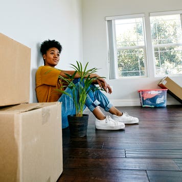 woman sitting on the floor in her new house with boxes around her
