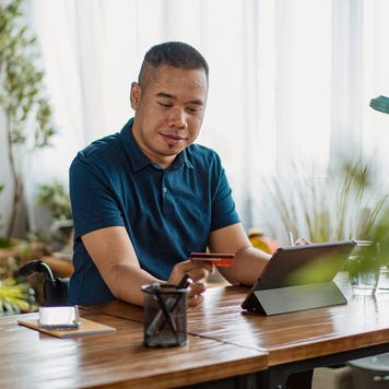 a man on his tablet holding a card in his hand