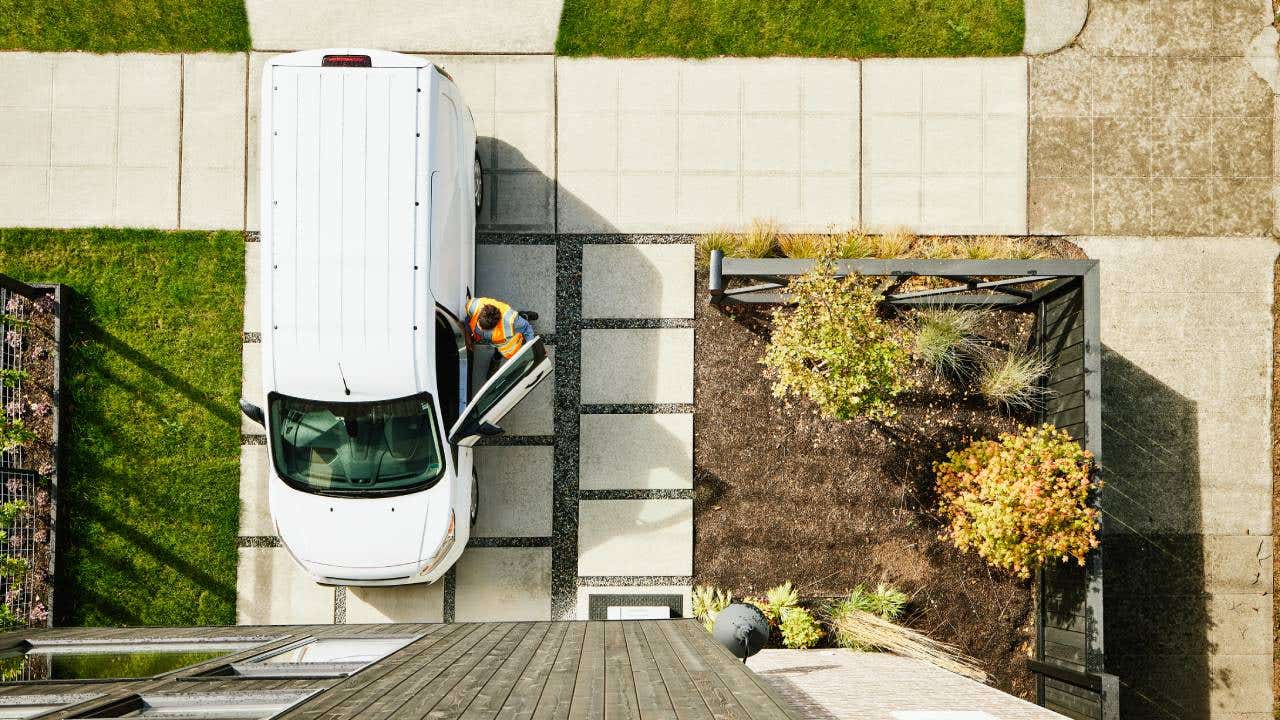 Overhead view of female delivery driver returning to van after delivering package to home