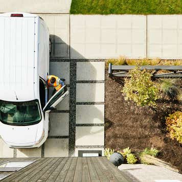 Overhead view of female delivery driver returning to van after delivering package to home