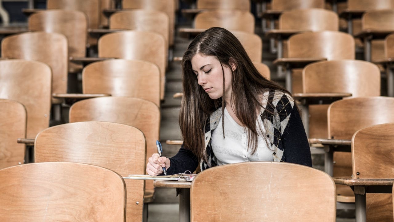 College student takes notes in a lecture hall