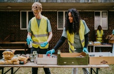 Female and male volunteers arranging food cans in box on table