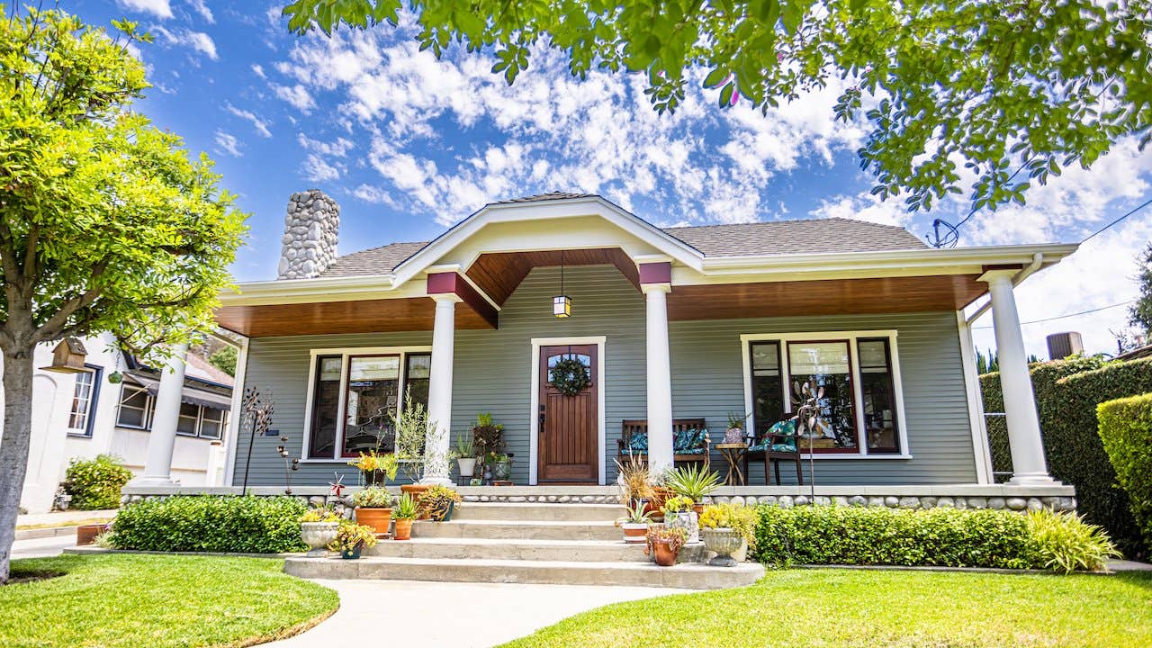 The exterior of a 1920s Craftsman bungalow home with white pillars