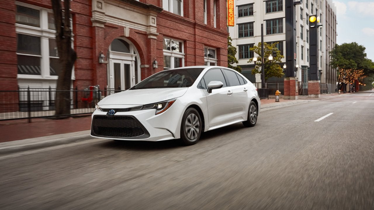 Driving through the city in a white 2022 Toyota Corolla Hybrid