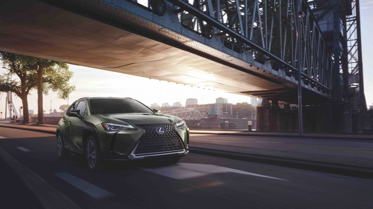 Driving a green 2022 Lexus UX under a bridge in the city