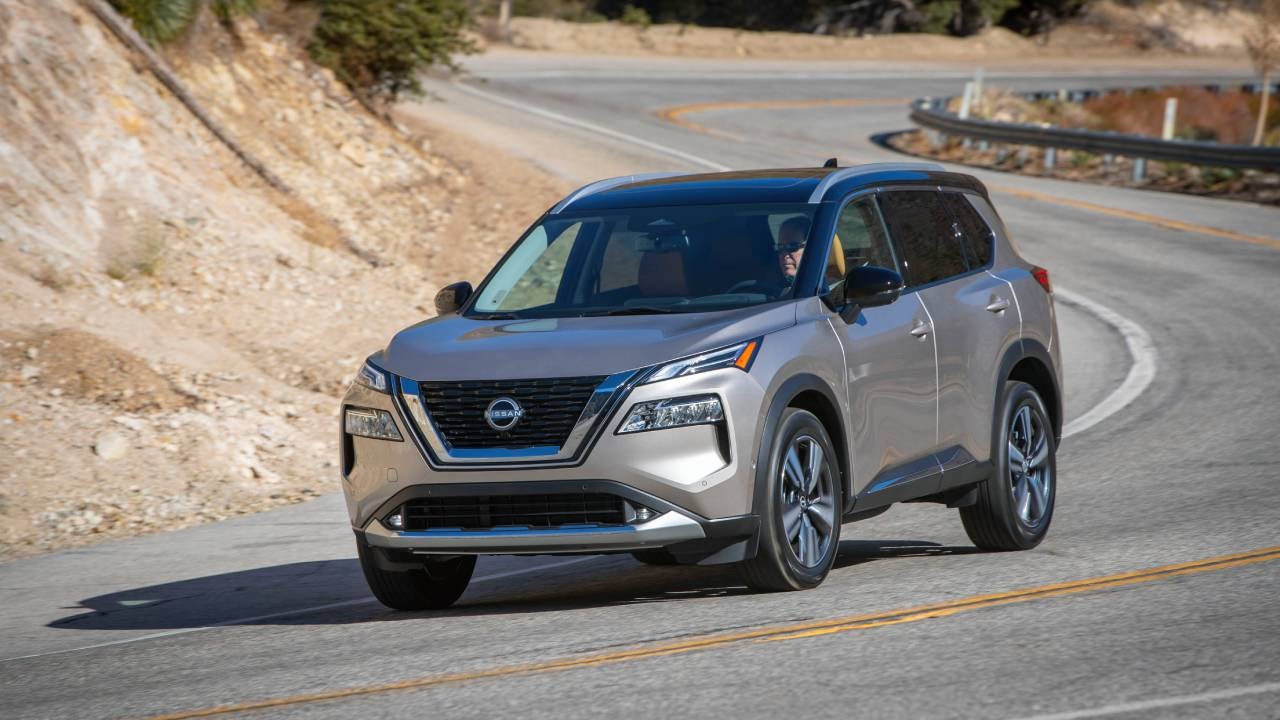A silver 2022 Nissan Rogue driving down a winding road