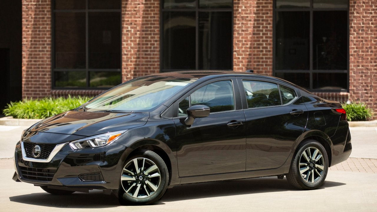 A black 2022 Nissan Versa parked in front of a brick building