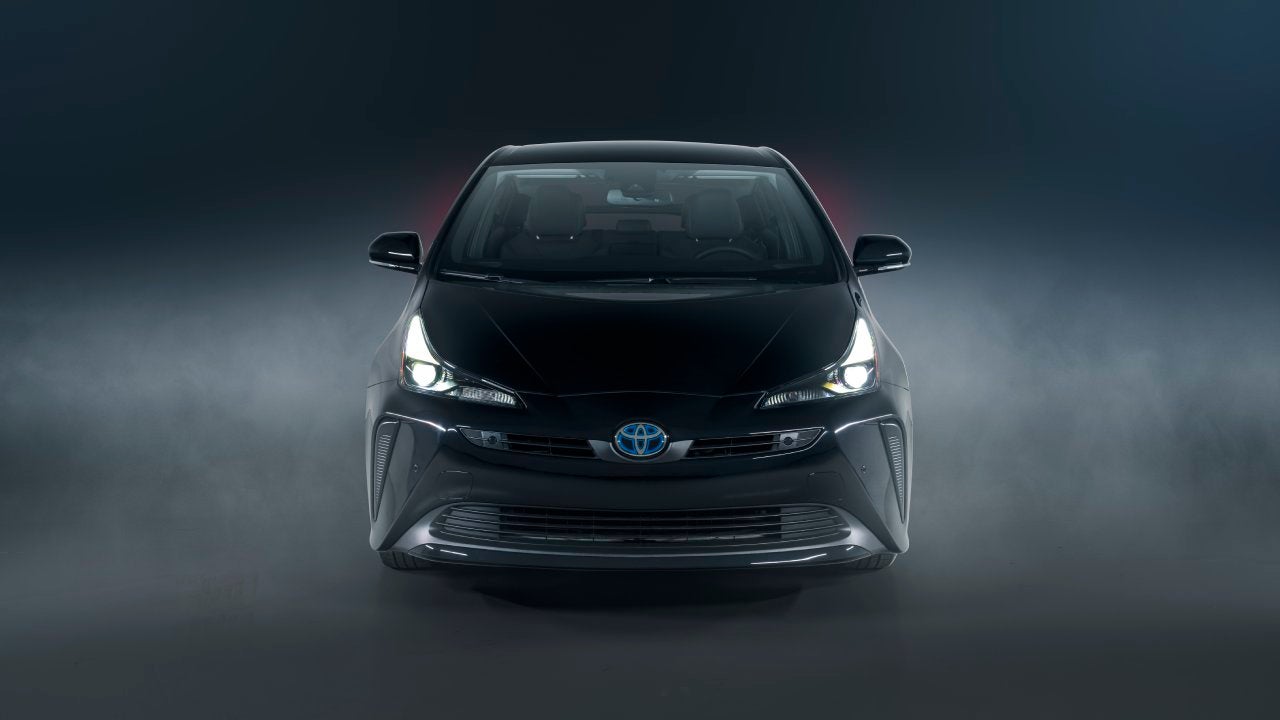 A black 2022 Toyota Prius parked in front of a black smoky backdrop