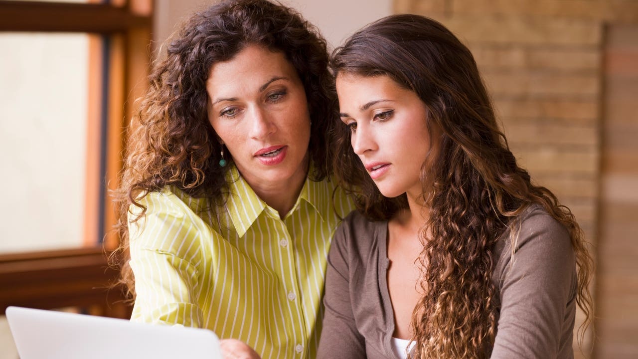 Mother and daughter look at a laptop