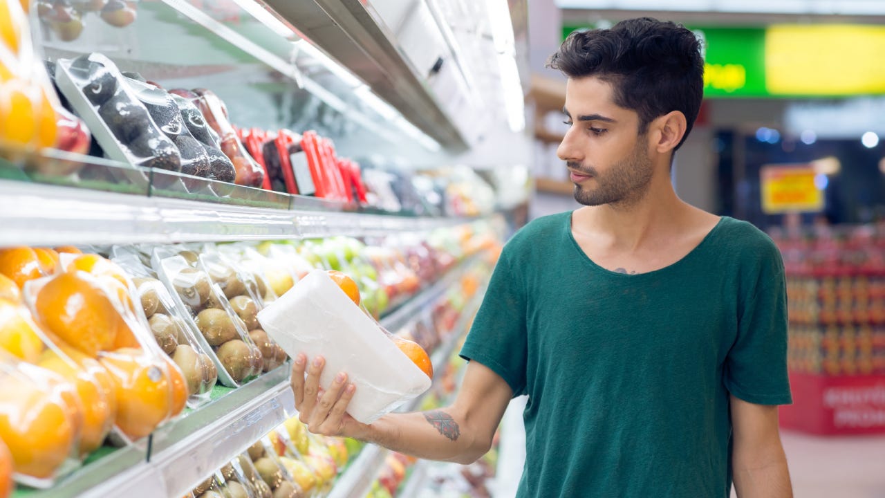 Young man choosing oranges in the supermarket