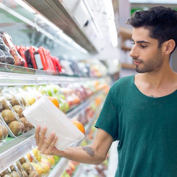 Person shopping at grocery store choosing oranges in the supermarket