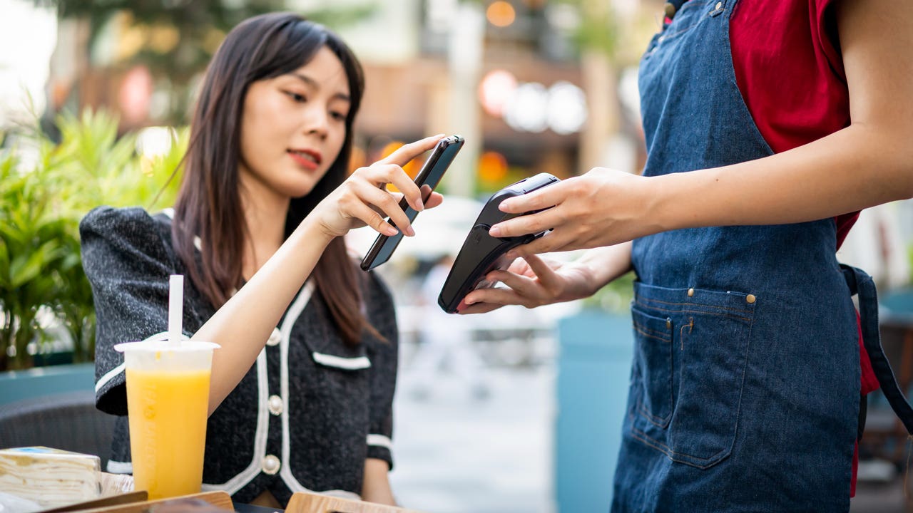 woman paying with her phone at a cafe