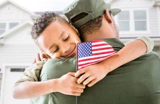 Soldier hugging patriotic son outside house