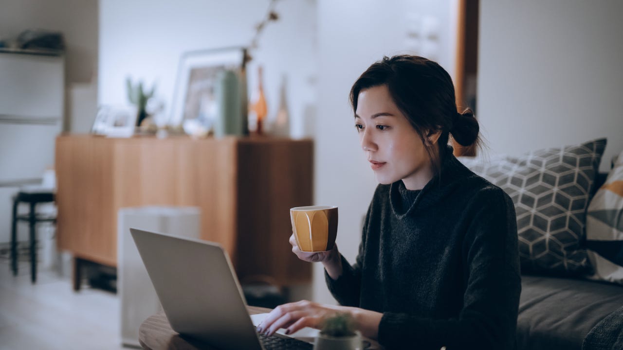 Busy concentrated young Asian woman working from home, working on laptop till late in the evening at home. Home office, overworked, deadline and lifestyle concept
