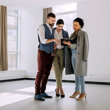 Real estate agent showing a property plans to a couple