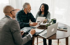 Two home buyers and a realtor discussing details at a round table