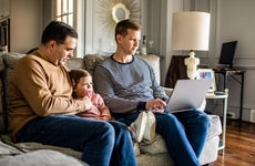 couple sitting in the living room with young daughter and working on computer