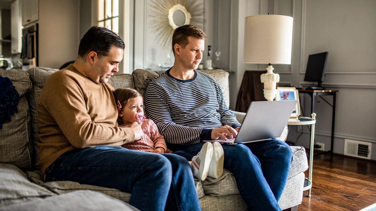 couple sitting in the living room with young daughter and working on computer