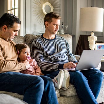 couple sitting in the living room with young daughter and working on computer