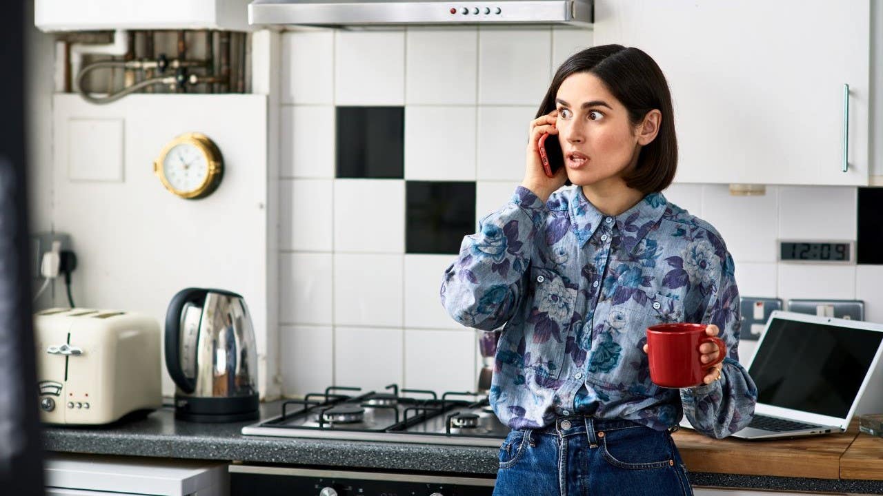 Person standing in a kitchen looking surprised while on a phone call