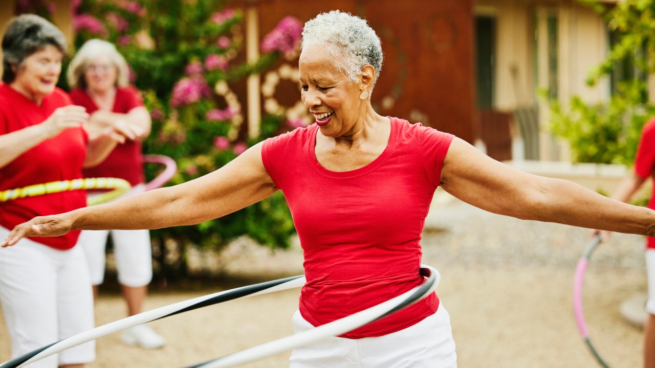 senior female dance group practicing with spinning plastic hoops in backyard