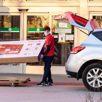 Target employees help a customer put a large screen TV into a vehicle