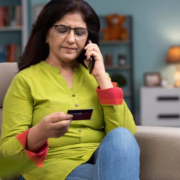 woman on the phone holding a credit card sitting on a couch