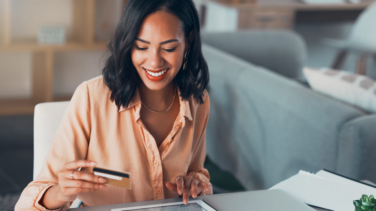 Shopping for online purchase with credit card and tablet, buying products for house and making payment with technology. Smiling and cheerful woman holding debit card for banking, budget and bills