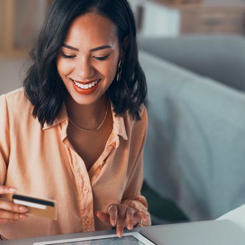 Shopping for online purchase with credit card and tablet, buying products for house and making payment with technology. Smiling and cheerful woman holding debit card for banking, budget and bills