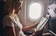 Happy woman reading a magazine in an airplane.