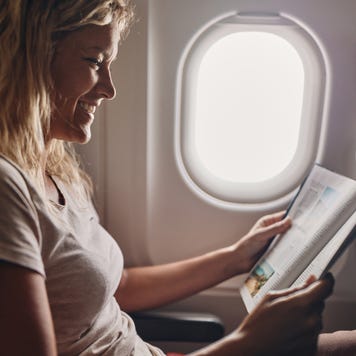 Happy woman reading a magazine in an airplane.