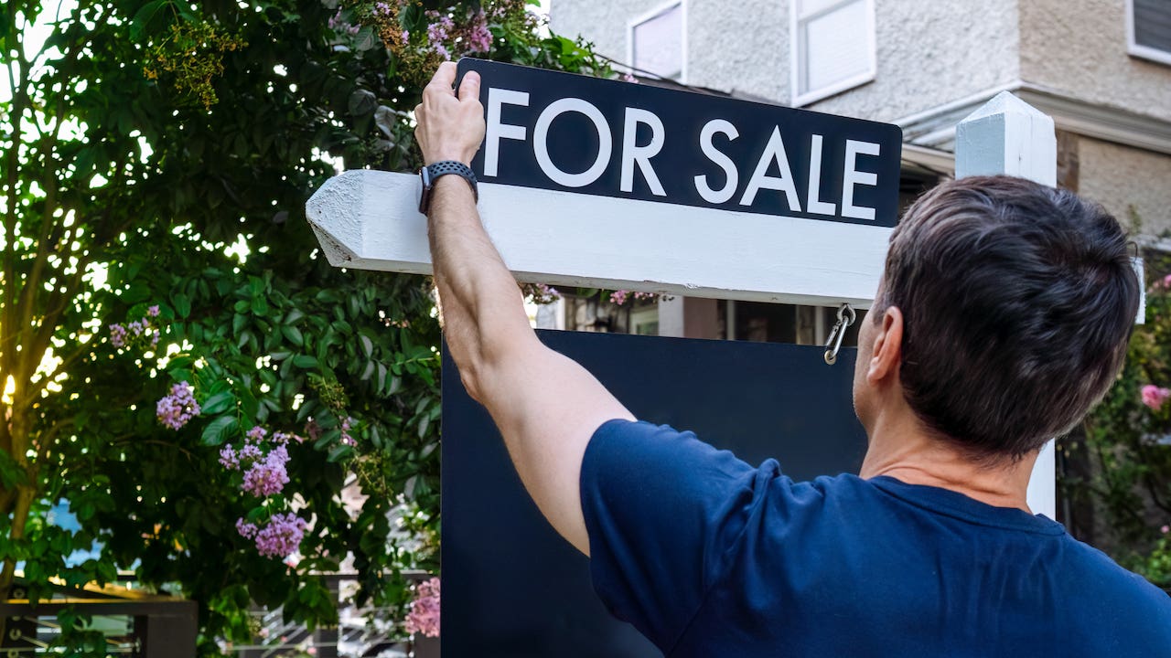 home prices dropping - realtor putting up for sale sign outside house