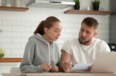 Focused serious couple checking bills sitting together at kitchen table