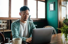 Young professional man working on a laptop in a cozy space with coffee