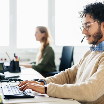 Man Working At Computer And Talking To Clients On Phone