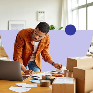 design image of an adult leaning voer a table looking at laptop and there are boxes on the table