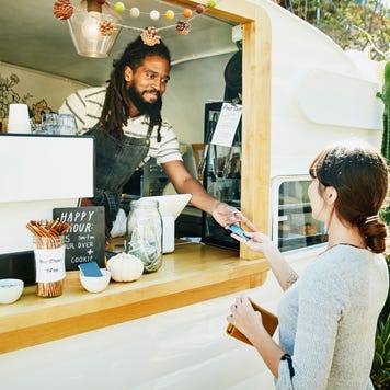 Smiling food truck owner taking credit card for payment from customer