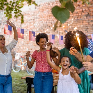 Multi-generation family waving sparklers outdoors on an American national holiday