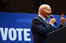 President Biden speaking at podium with a 'Vote' sign behind him