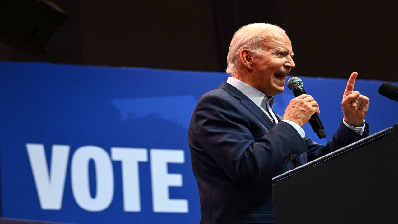 President Biden speaking at podium with a 'Vote' sign behind him