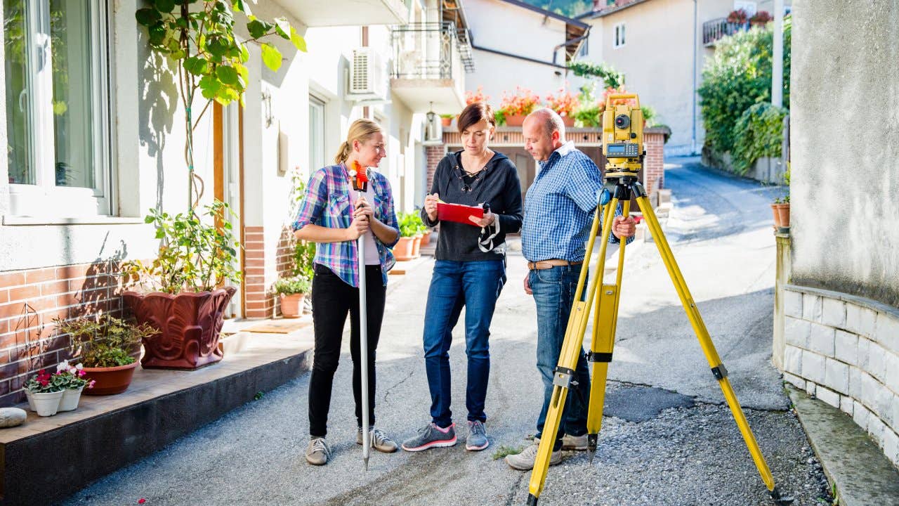 Team of Surveyors Planning and Discussing on Village Street