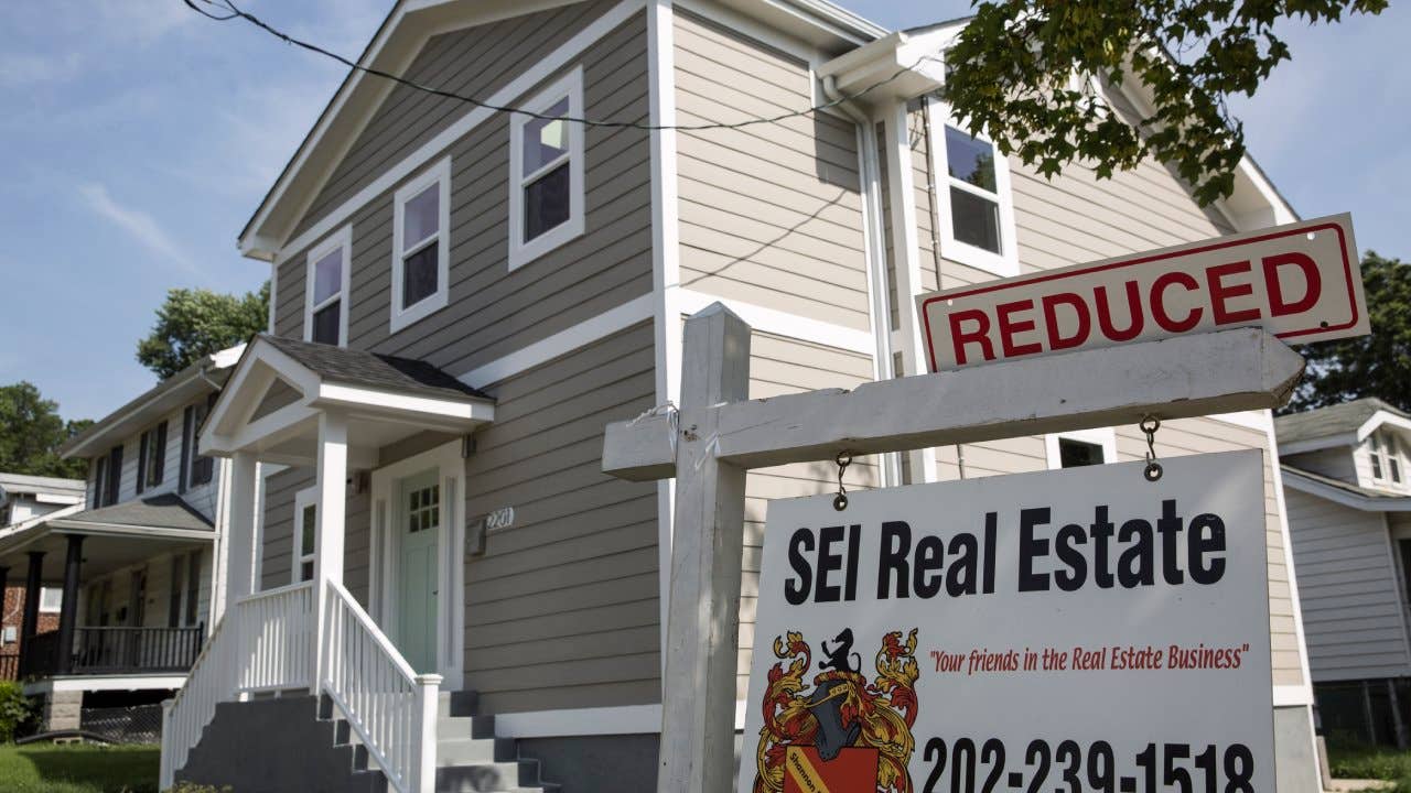 Gray house with a 'For Sale' sign that says, "Reduced"