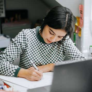 Hispanic latina college student works on assignment in her dorm room