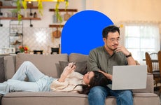 single vs married housing costs - couple sitting on couch looking at phone and laptop