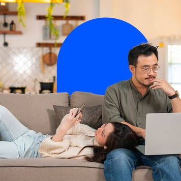 single vs married housing costs - couple sitting on couch looking at phone and laptop
