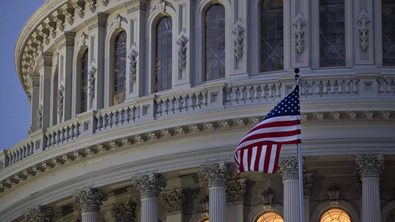 The American flag flies outside the U.S. Capitol before sunrise