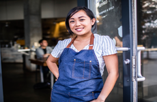 Asian woman wearing apron outside of storefront
