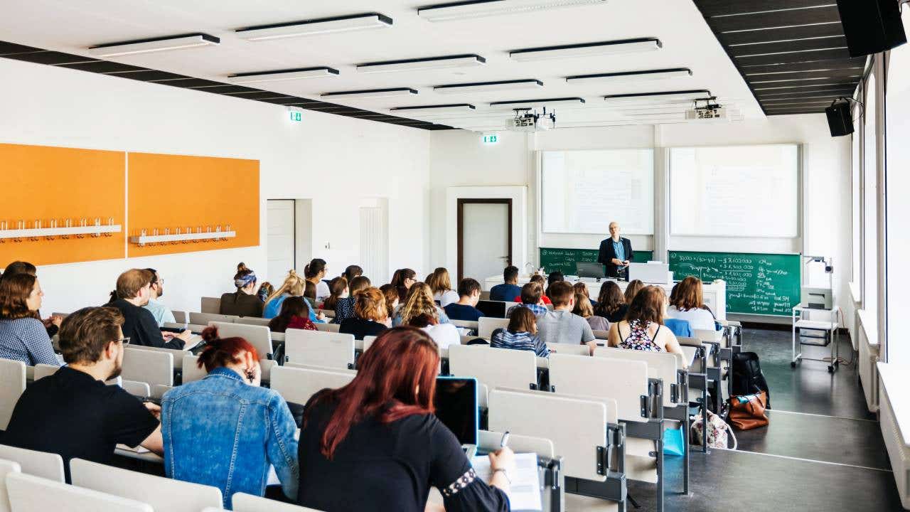 A university lecturer addressing his students in a modern lecture hall.